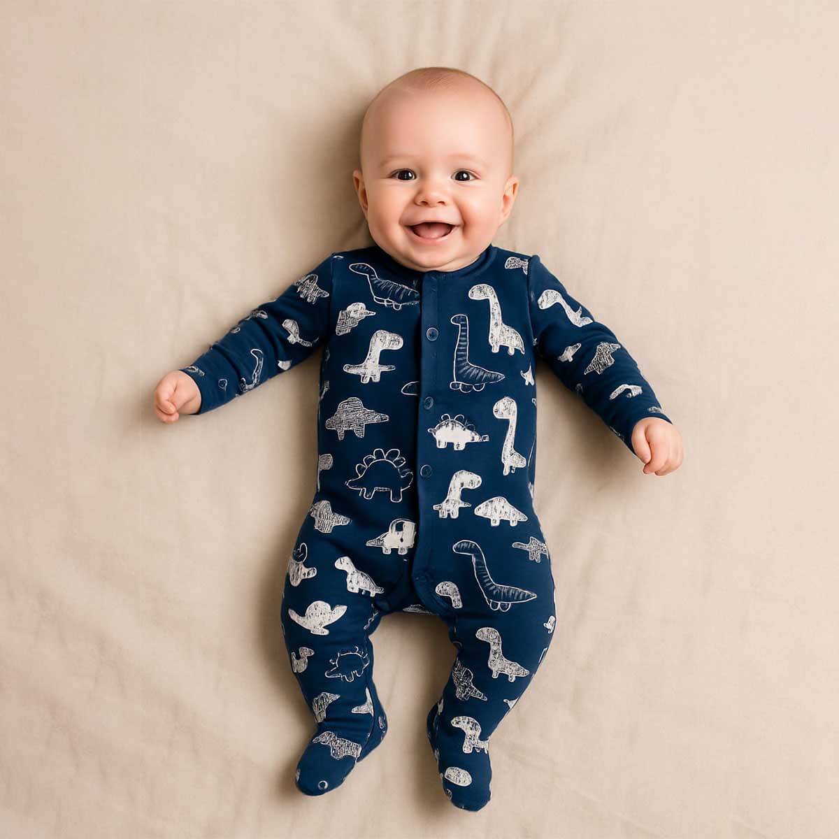 A toddler is wearing a Dino Doodle Midnight Sleepsuit