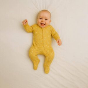 A toddler is wearing a Golden Meadow Animal Sleepsuit