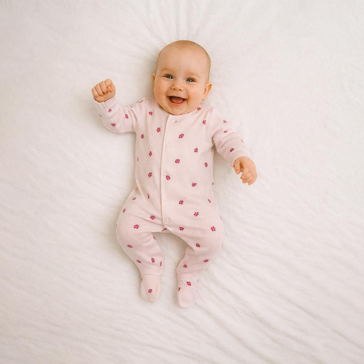 A toddler is wearing a Little Ladybug Snuggle Sleepsuit