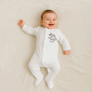 A toddler is wearing a Little Roar Classic Sleepsuit