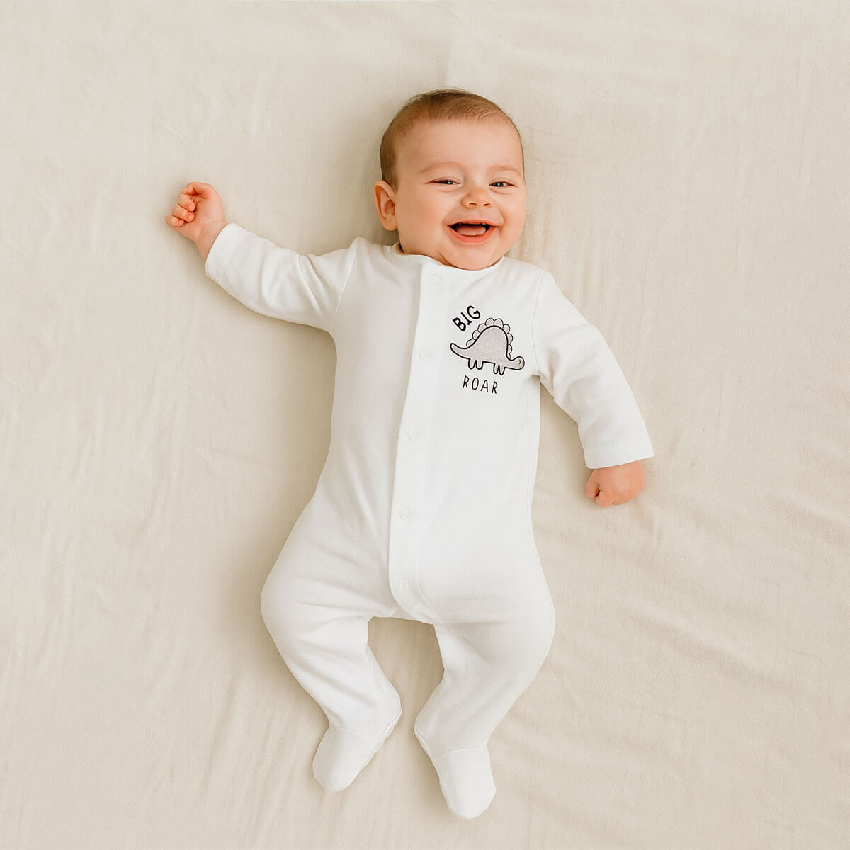 A toddler is wearing a Little Roar Classic Sleepsuit