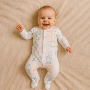 A toddler is wearing a pooh and honey meadow sleepsuit