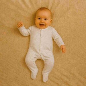 A toddler is wearing a Pure Sand Comfort Sleepsuit