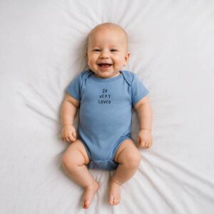 A toddler is wearing a so very loved baby bodysuit