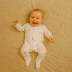 A toddler is wearing a Squirrel and Spike Dreams Sleepsuit