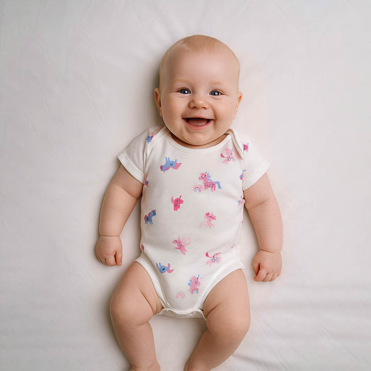 A toddler is wearing a unicorn reverie baby bodysuit