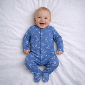 A toddler is wearing a Blue Dino Whisper Sleepsuit