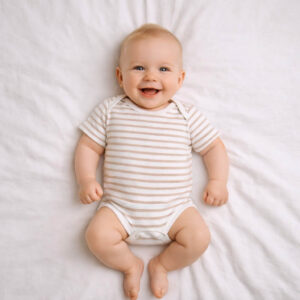 A toddler is wearing a Soft Sand Stripes Bodysuit