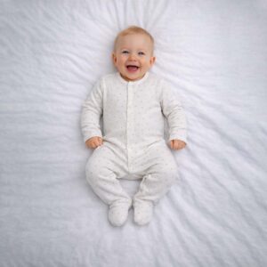 Baby wearing a baby dotted sleepsuit with soft cream fabric and tiny dot pattern