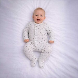 Baby wearing a baby sheep print sleepsuit with soft grey fabric and cute sheep pattern