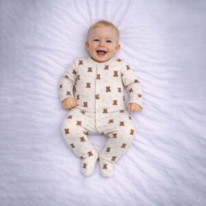 Baby wearing a baby teddy bear sleepsuit with cream fabric and cute teddy print