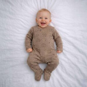Baby wearing a baby woodland animal sleepsuit with soft brown fabric and forest animal print