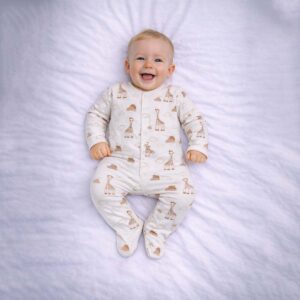 Giraffe print baby sleepsuit worn by baby showing cute giraffe and cloud design