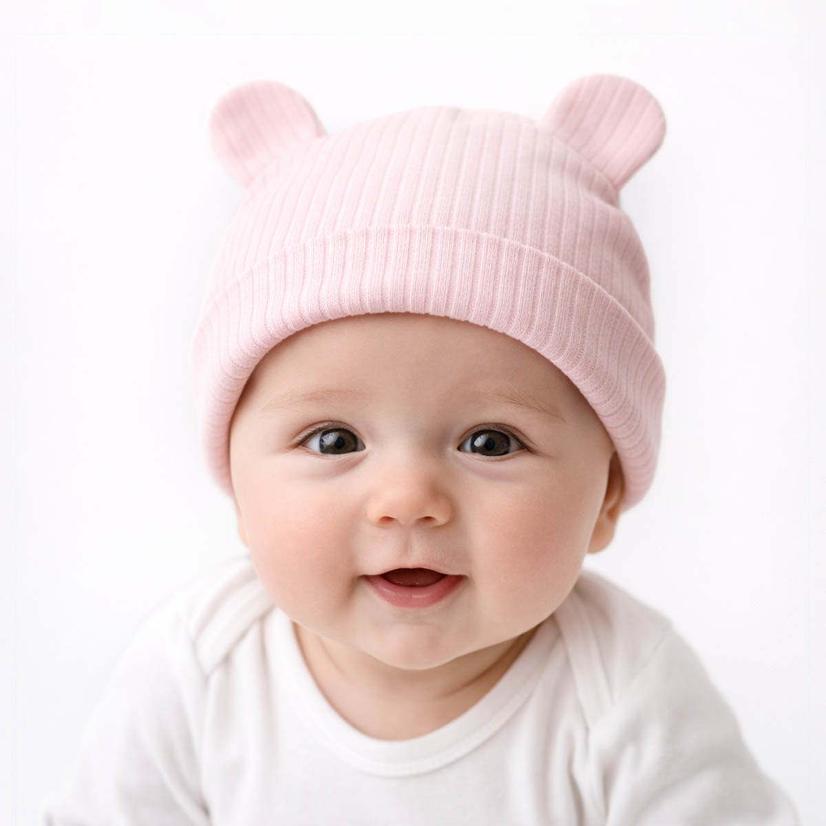 Newborn ribbed baby hat worn by baby featuring soft pink fabric and bear ears