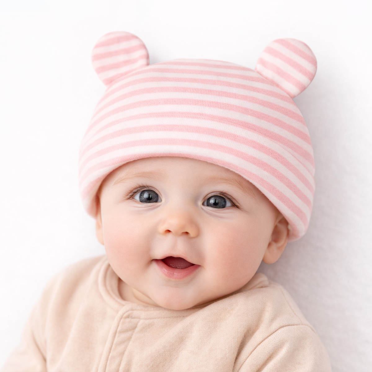 Newborn striped baby hat worn by baby with soft pink stripes and bear ears