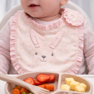 Pink bunny ruffle baby bib worn by a baby during feeding time