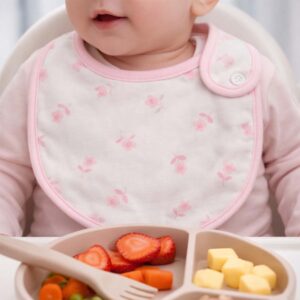 Pink floral baby bib worn by a baby during feeding time
