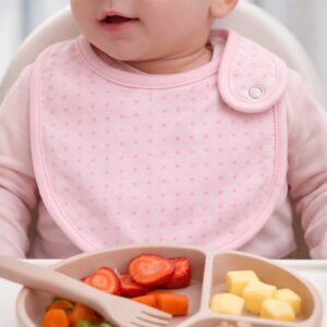 Pink polka dot baby bib worn by a baby during feeding time